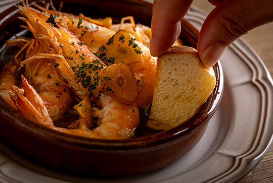 熱々のオイルで提供される天使の海老のアヒージョ