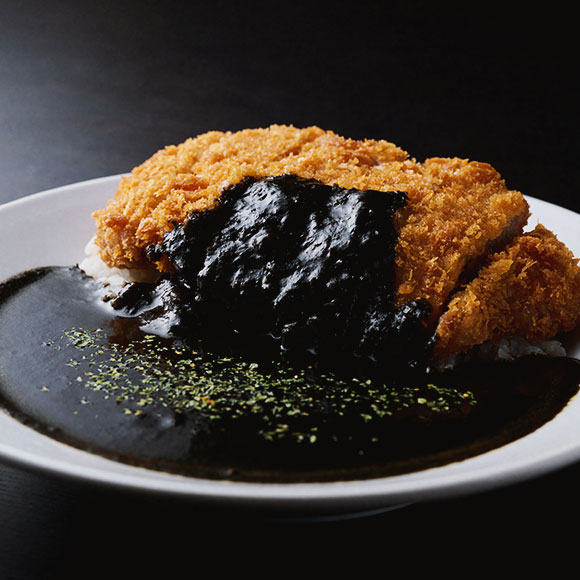 香味野菜を形がなくなるまで長時間煮込み、イカ墨の奥深いコクと野菜の旨味を合わせた人気の「カツ黒カレー」